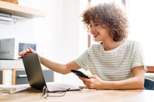 Chica de pelo rizado con la mano apoyada en un portátil preparada para hacer formación online