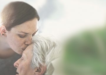 Mujer dándole un beso en la frente a su madre