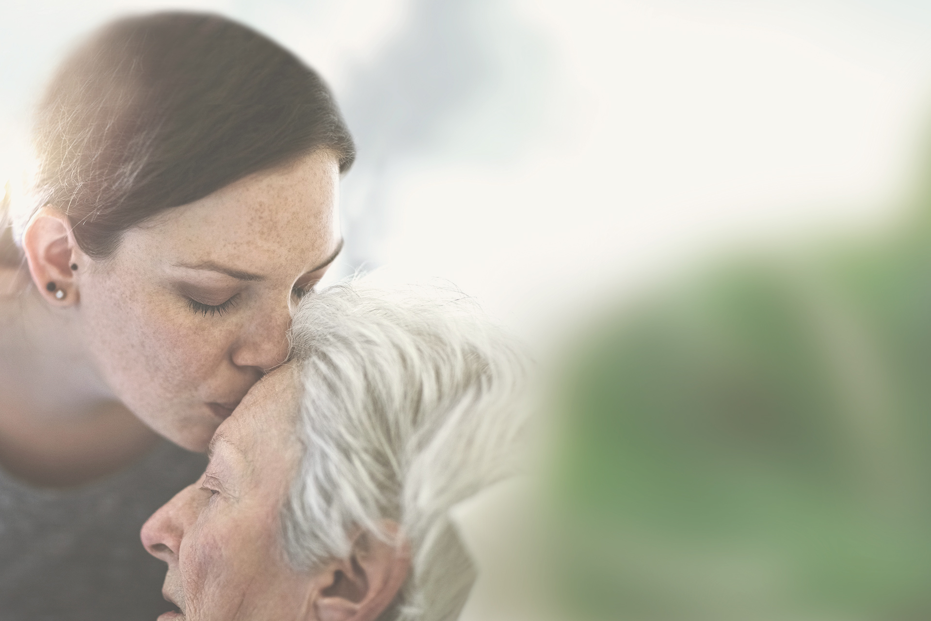 Mujer dándole un beso en la frente a su madre